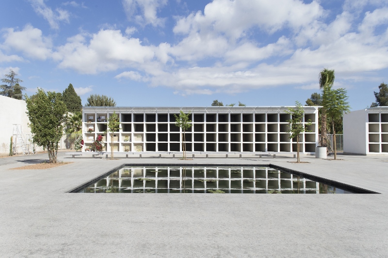 Fotografía de la piscina central del cementerio con el edificio de nichos al fondo.